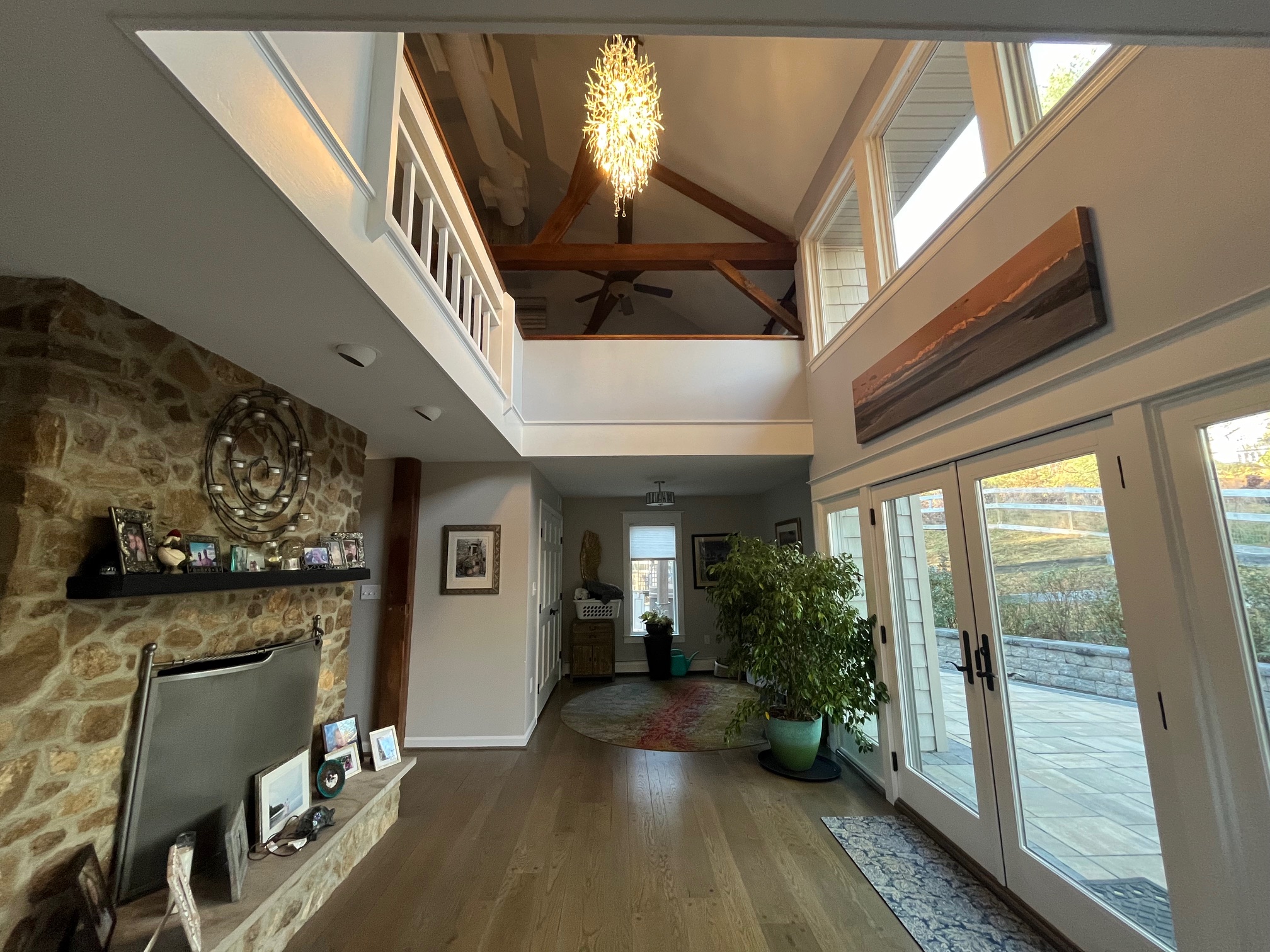 Renovated interior with timber beams, stone wall, and open loft by Buck Run Builders